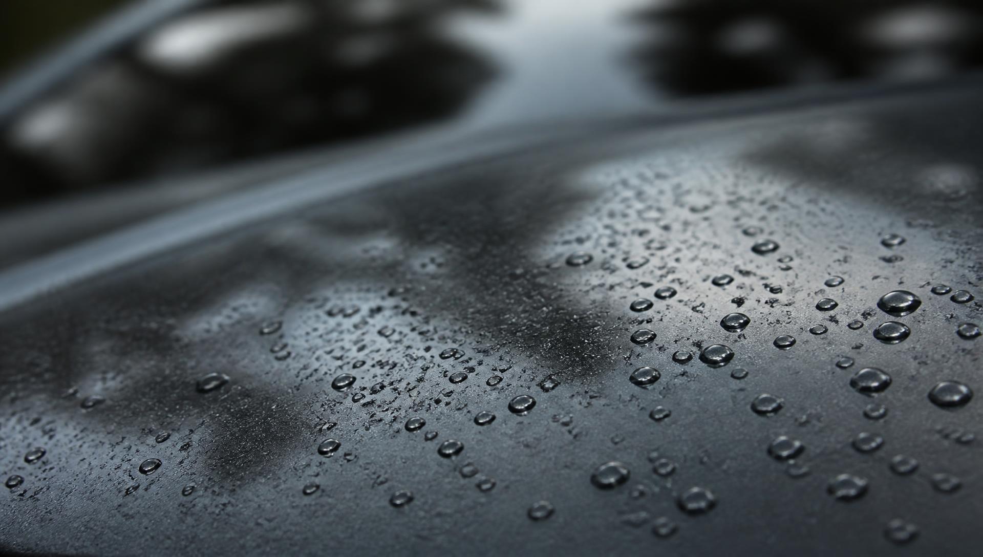 Close view of water beading on a freshly ceramic-coated dark car panel